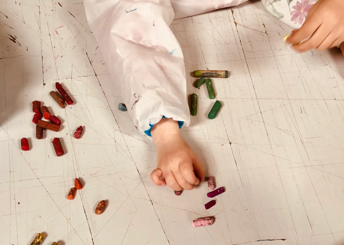 Des mains d'enfant qui pratiquent l'art avec des craies grasses